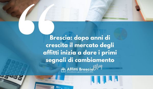 Sfondo con scrivania e fogli con grafici, scritta bianca su sfondo blu "Brescia: dopo anni di crescita il mercato degli affitti inizia a dare i primi segnali di cambiamento" logo bianco affitti Brescia con casetta stilizzata e scritta Blog